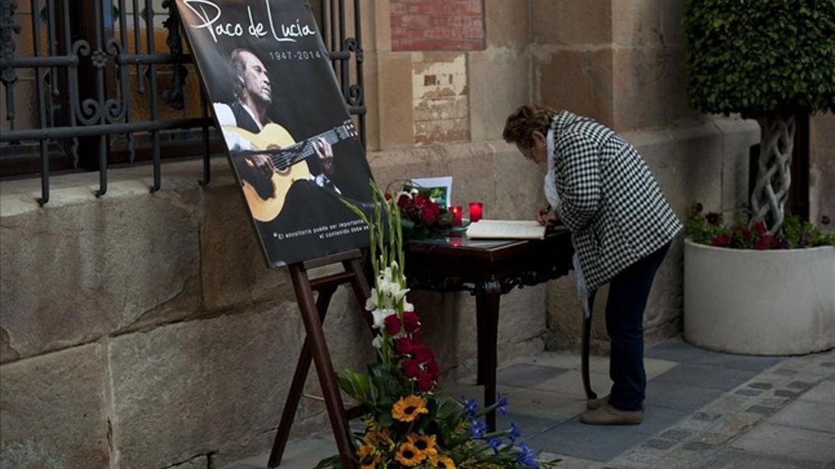 Una mujer firma en el libro de condolencias frente a un fotografía de Paco de Lucía en Algeciras