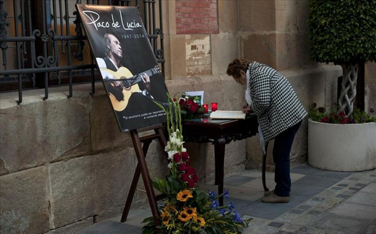 Una dona firma al llibre de condol davant una fotografia de Paco de Lucía a Algesires.