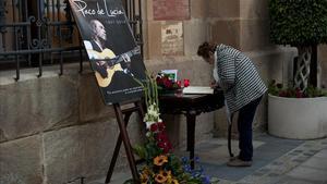 Una dona firma al llibre de condol davant una fotografia de Paco de Lucía a Algesires.