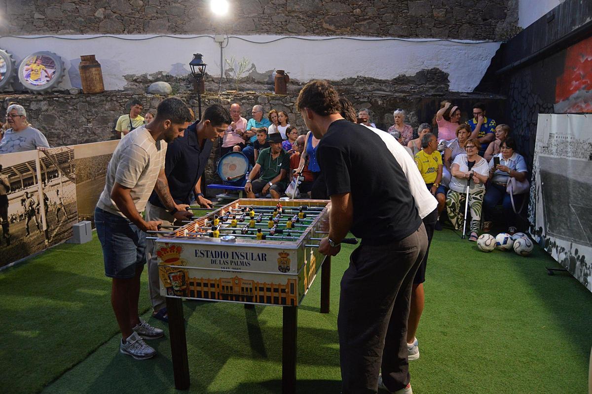 Imagen de varios de los asistententes jugando con el futbolín restaurado.