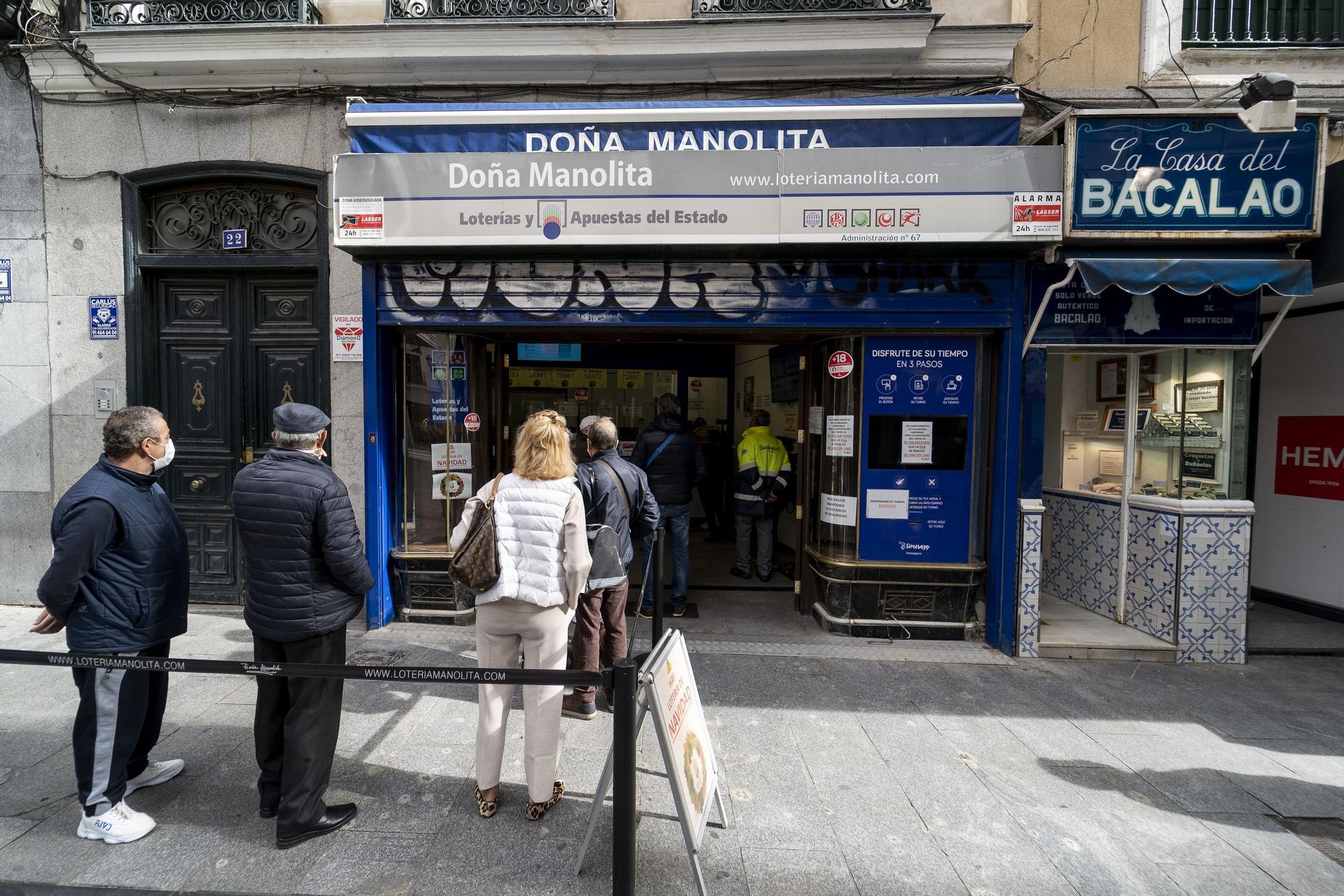 Un grupo de personas esperan a las puertas de la administración de lotería Doña Manolita