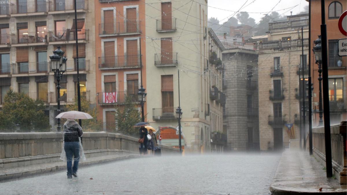 Una dona protegint-se de la pluja al Pont de Pedra de Girona.
