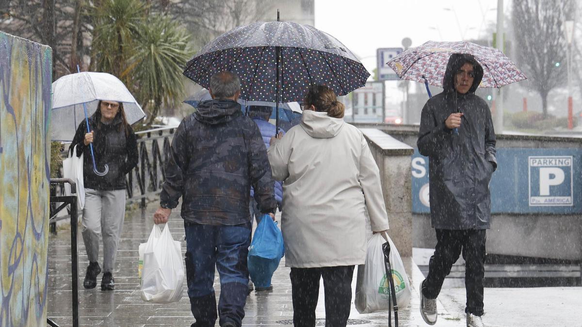 Personas bajo el aguacero, ayer en la Avenida de Castelao de Vigo.