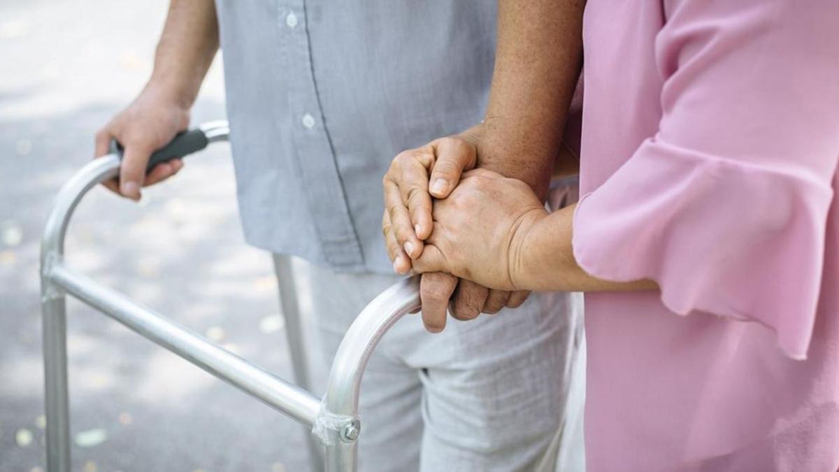 Una mujer ayuda a un hombre mayor a caminar. | L. O.