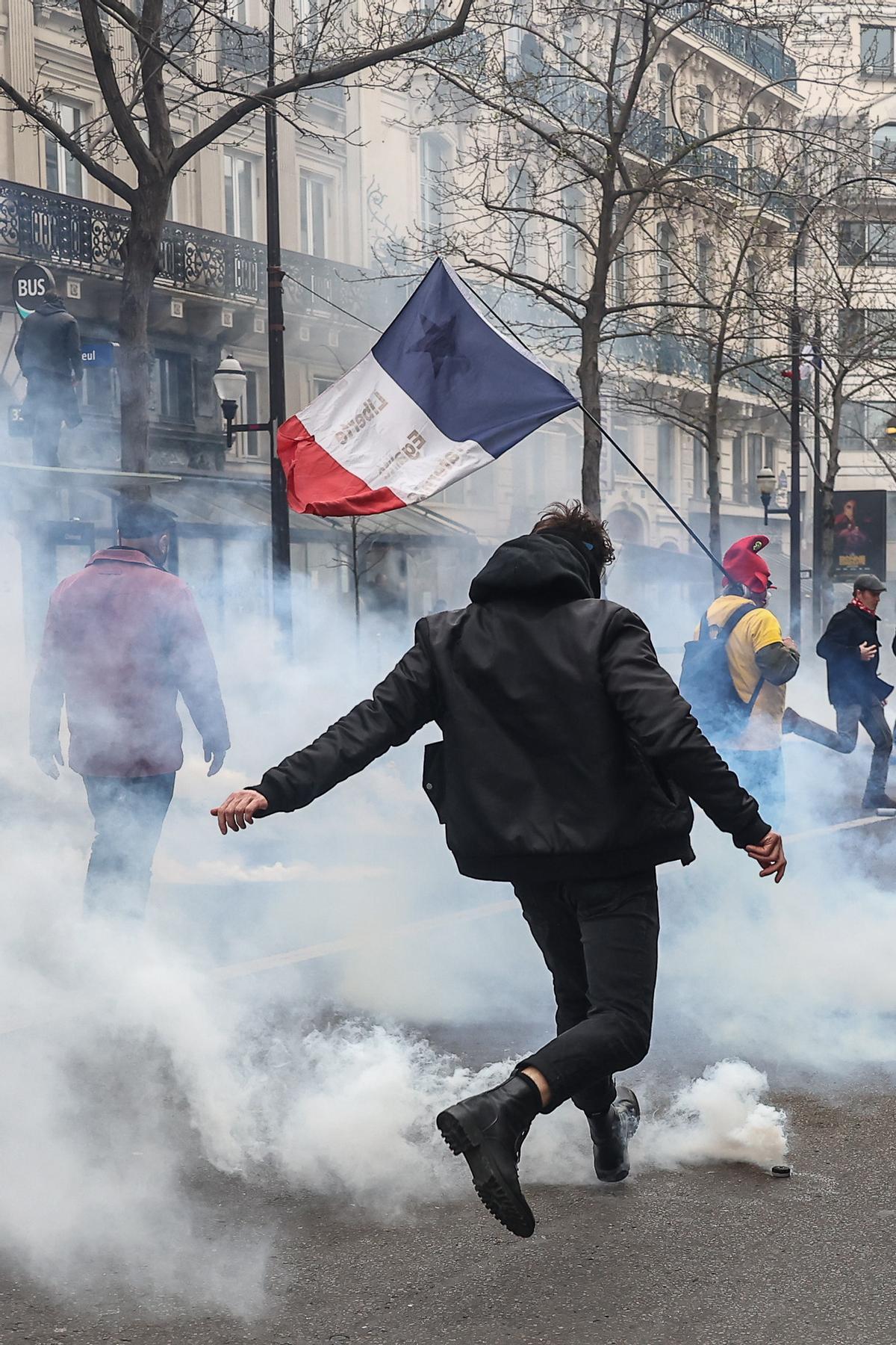 Paris (France), 23/03/2023.- A Protester kicks a tear gas bomb during clashes with anti-riot police, during a protest against government pension reform in Paris, France, 23 March 2023. Protests continue in France after the French prime minister announced on 16 March 2023 the use of Article 49 paragraph 3 (49.3) of the French Constitution to have the text on the controversial pension reform law be definitively adopted without a vote in the National Assembly (lower house of parliament). The bill would raise the retirement age in France from 62 to 64 by 2030. (Protestas, Francia) EFE/EPA/MOHAMMED BADRA