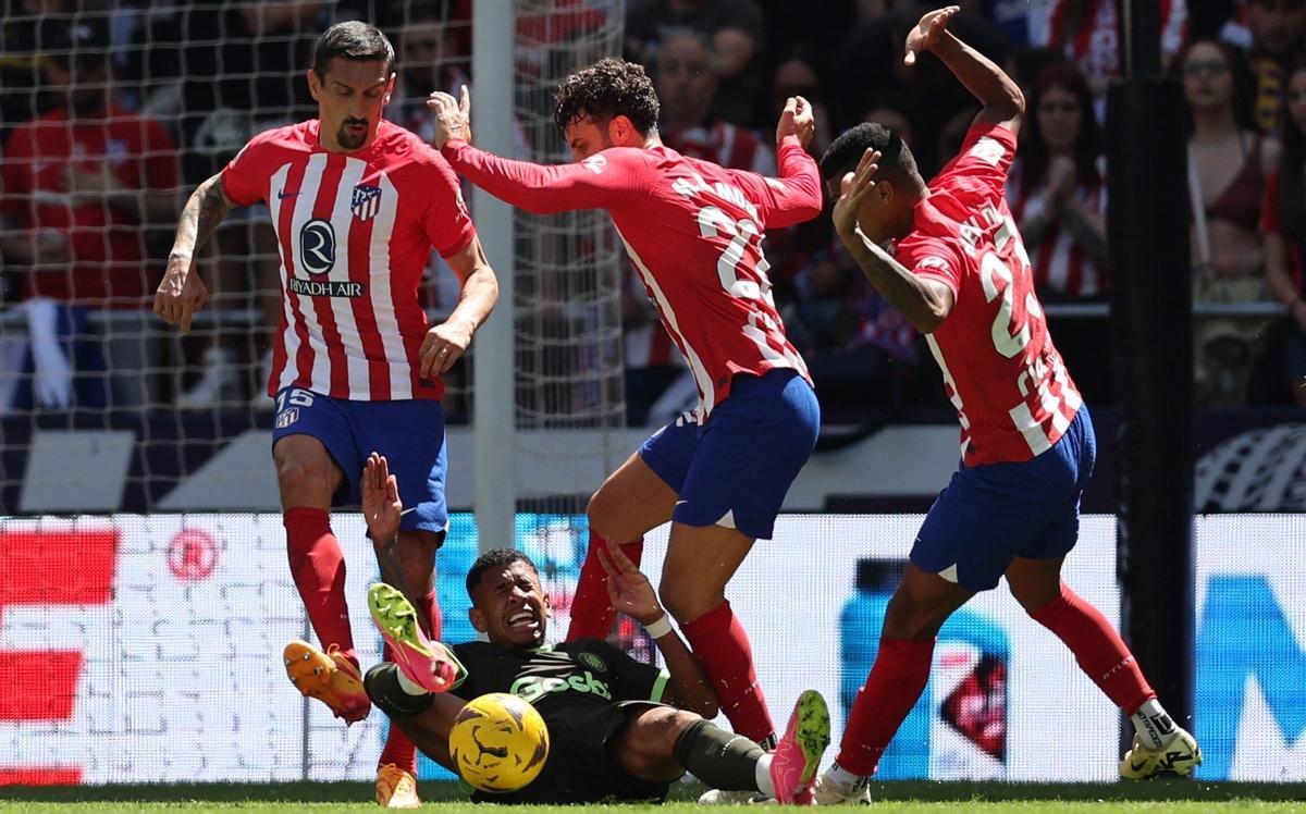 Sávio, derribado por tres contrarios en el área del Atlético.