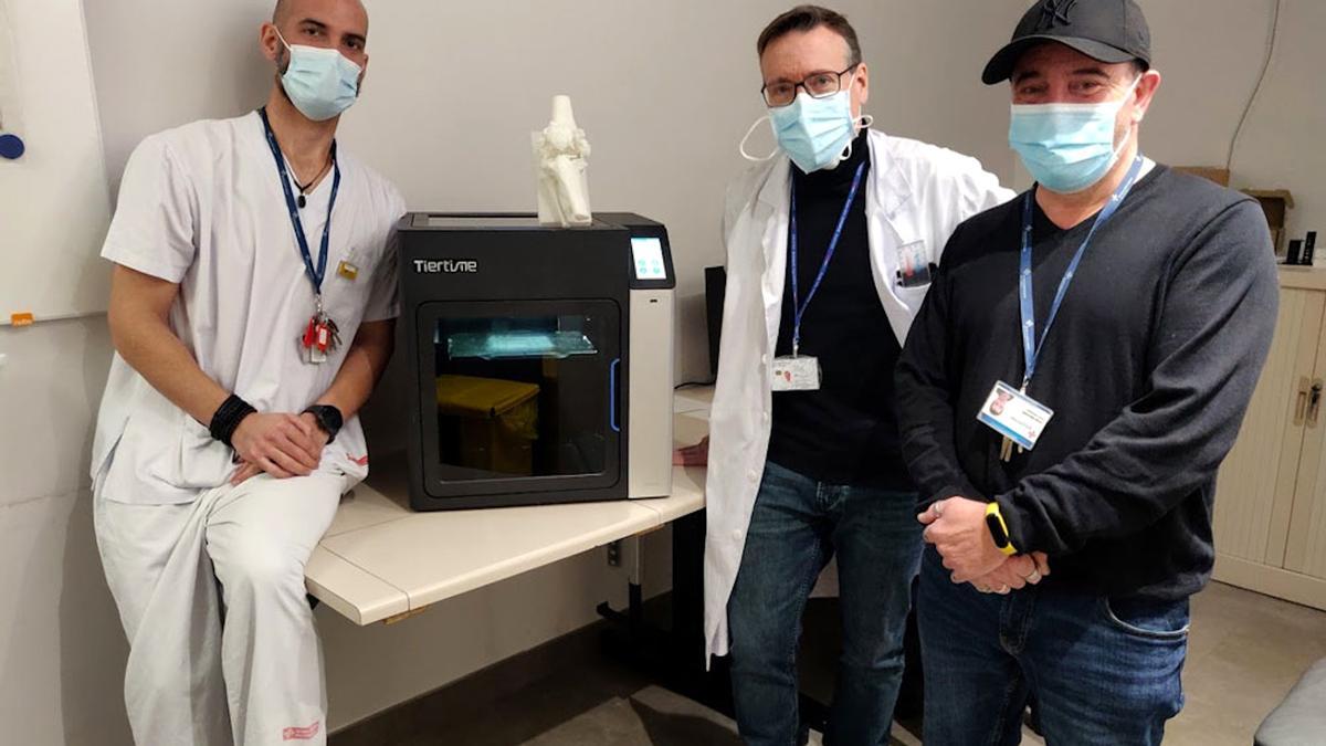 Personal mèdic i sanitari de radiologia i traumatologia de l&#039;hospital de Palamós, al costat d&#039;una impressora 3D amb un model anatòmic dels que es fan servir per planificar cirurgies .