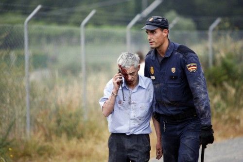 An injured passenger is helped by a policeman after a train crashed near Santiago de Compostela