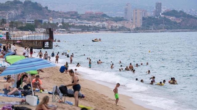 Persones refugiant-se de la calor en una platja de Badalona.
