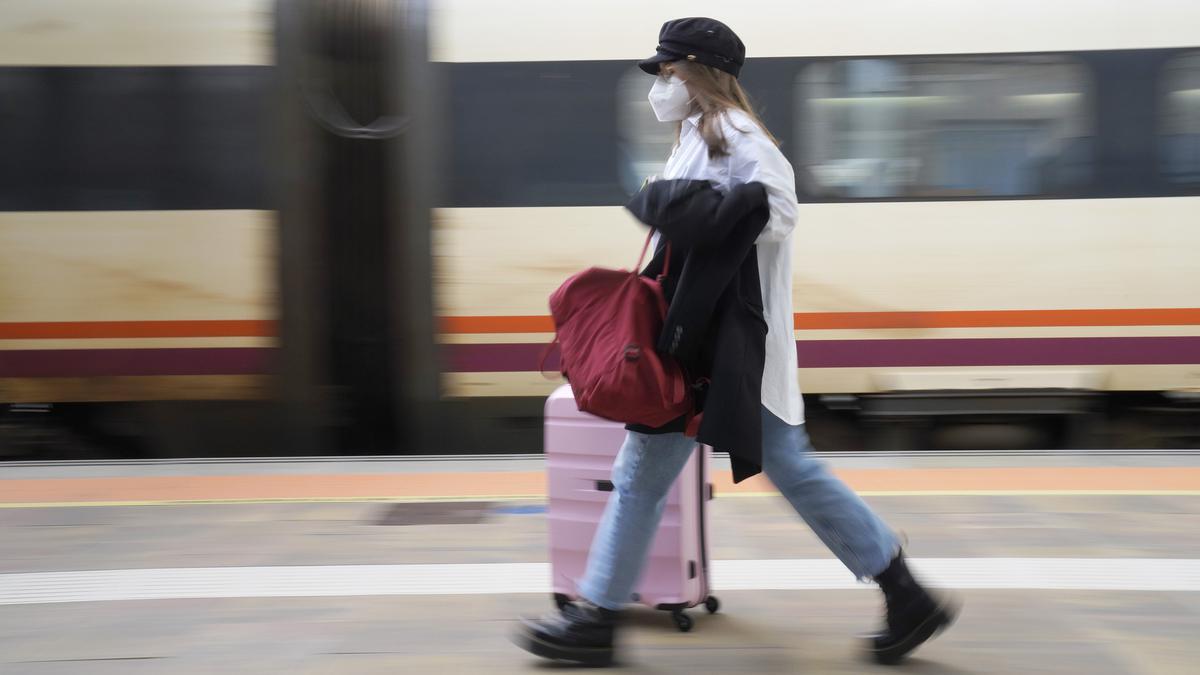 Una mujer con su maleta en una estación de tren.