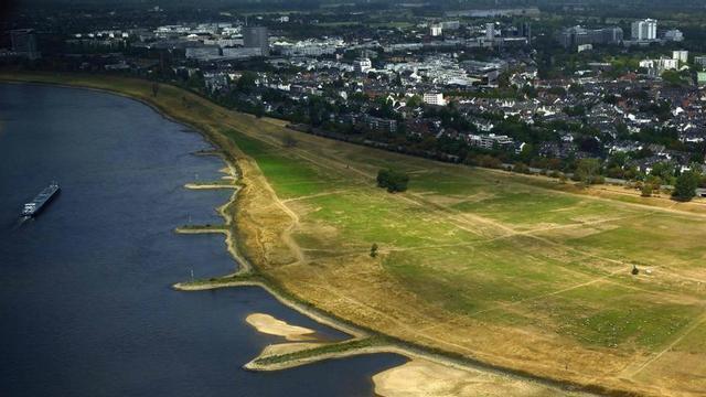 Un vaixell navega al costat del llit parcialment sec del riu Rin al seu pas per Düsseldorf. | INA FASSBENDER / AFP