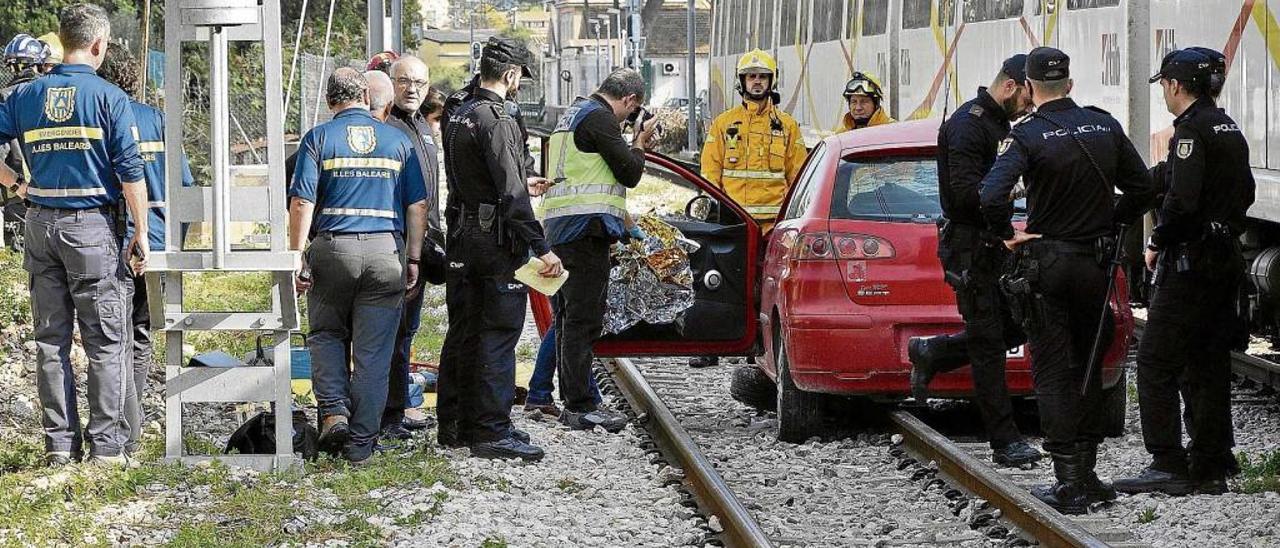 Policías y bomberos, junto al coche que fue arrollado por un tren en un paso a nivel en Palma.