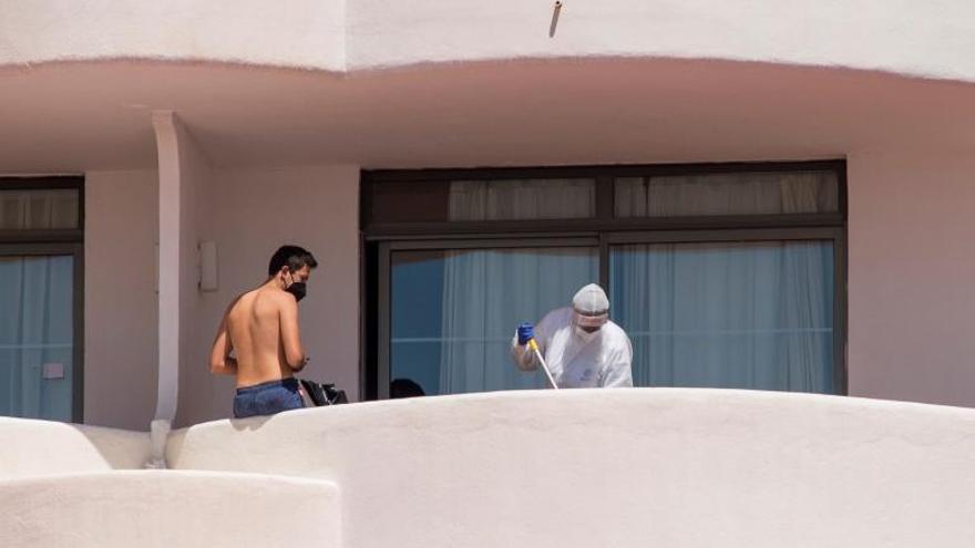 Uno de los jóvenes confinados en el hotel COVID de Mallorca y un trabajador del establecimiento limpiando la terraza. 