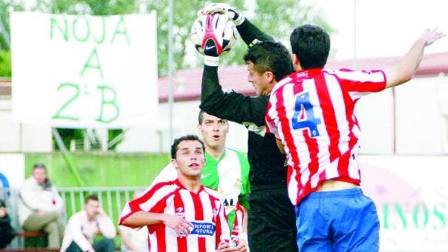 El portero del Noja Marcano atrapa un balón en presencia de los rojiblancos Omar y Carlos.