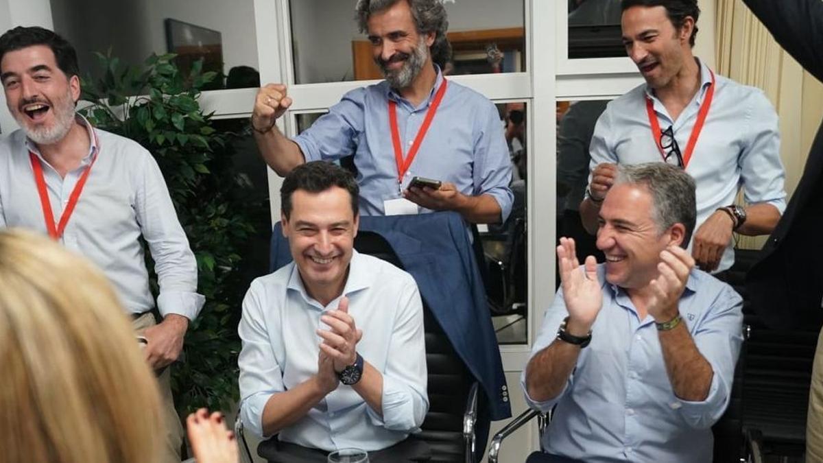 Juanma Moreno y Elías Bendodo celebran la noticia de la mayoría absoluta junto a varios asesores. /  L. O.