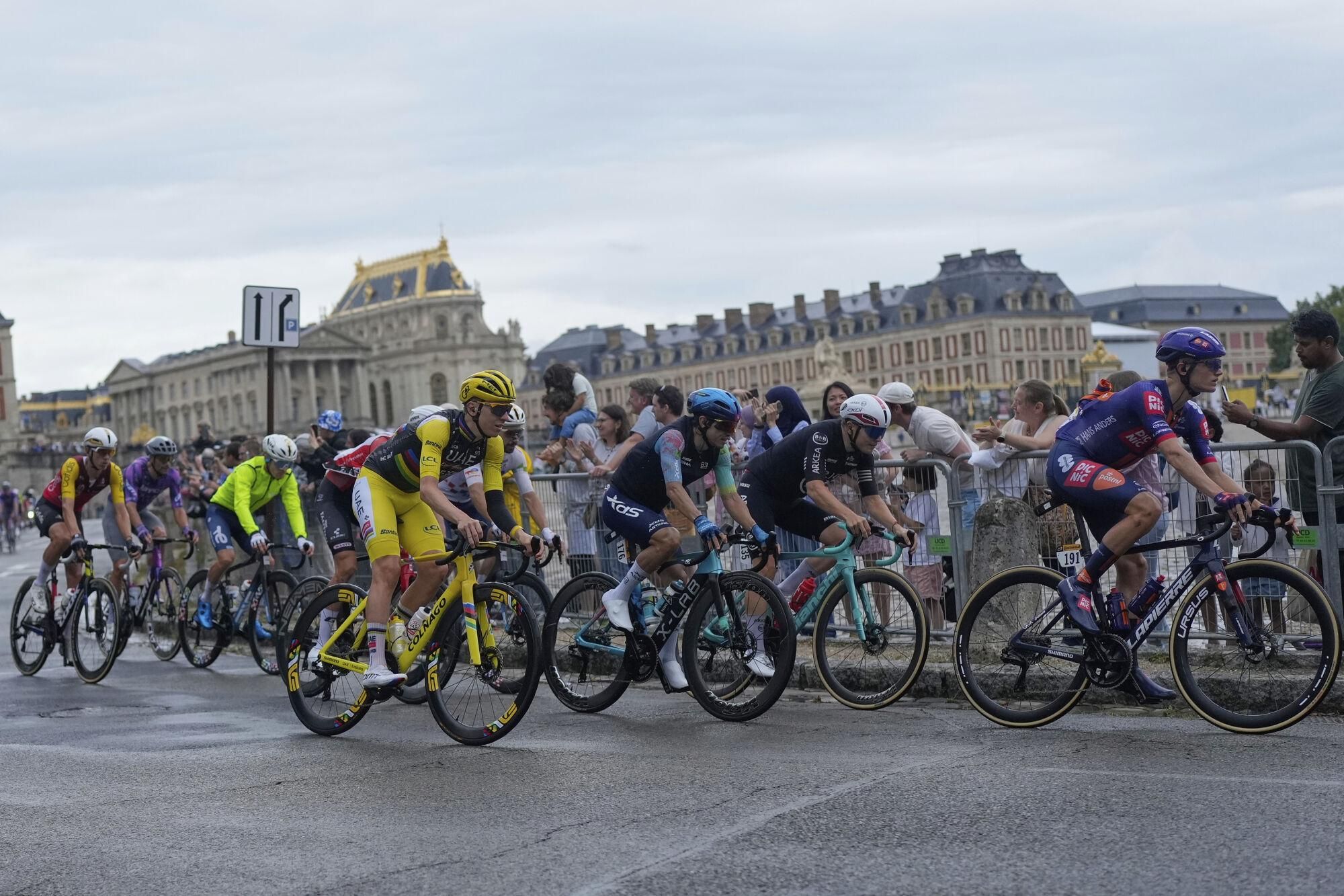 Britain's Oscar Onley, far right, and Slovenia's Tadej Pogacar, wearing the overall leader's yellow jersey, pass Chateau de Versailles during the twenty-first stage of the Tour de France cycling race over 132.3 kilometers (82.1 miles) with start in Mantes-la-Ville and finish on the Champs-Elysees in Paris, France, Sunday, July 27, 2025. (AP Photo/Mosa'ab Elshamy)