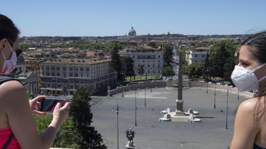 Dos mujeres con mascarilla hacen una foto en Roma.