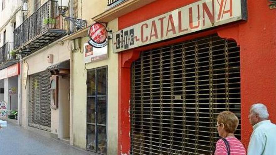 Vianants passejant per davant del cinema Catalunya, tancat des del maig del 2013, ahir al migdia