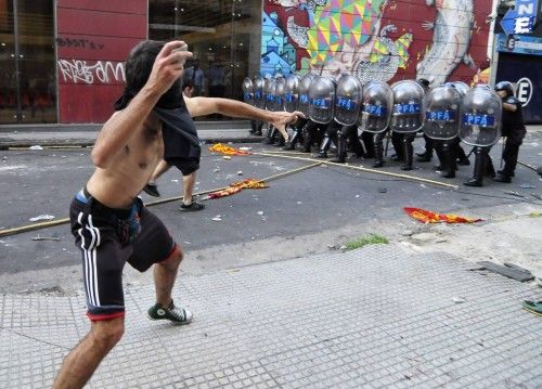 An activist hurdles stones to anti-rio policemen guarding the Tucuman provincial house in Buenos Aires
