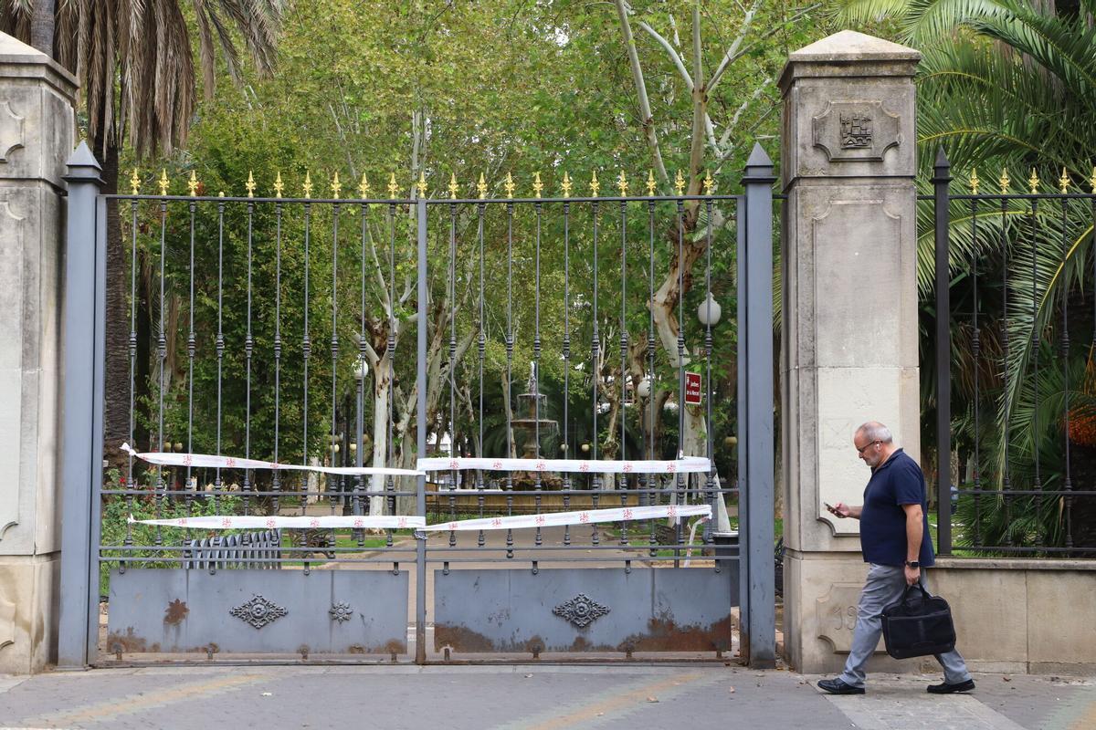Un hombre camina junto a la puerta del Parque de Colón, cerrado a causa de un temporal.