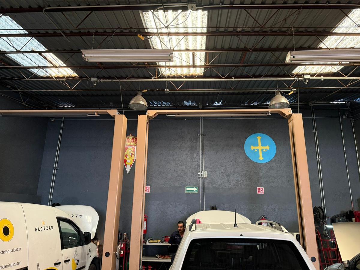 El escudo del Sporting y la bandera de Asturias, en una de las paredes del taller.