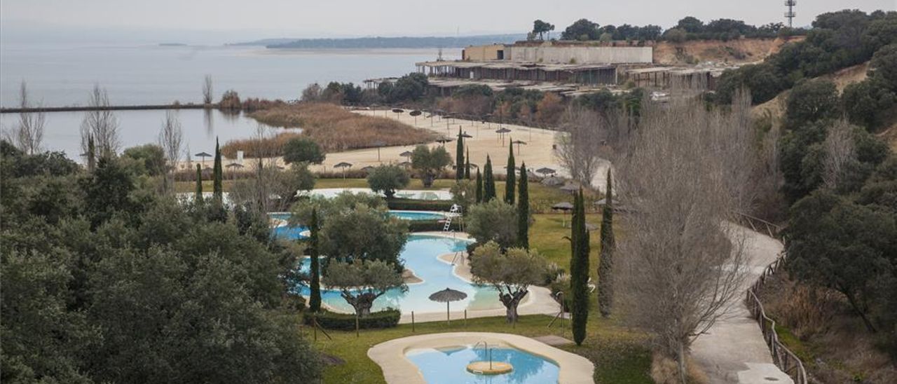 Vista de las piscinas, la playa artificial y el esqueleto del que iba a ser el segundo hotel del complejo.