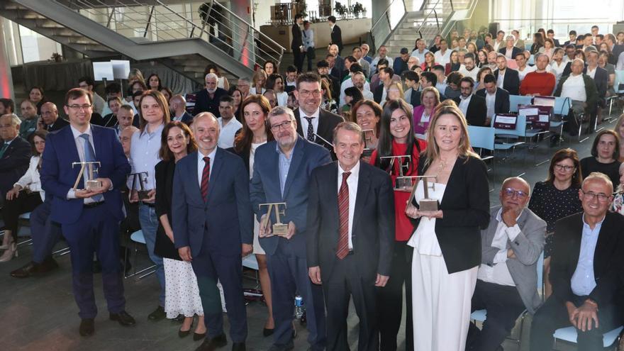 Foto de familia de los premiados con David Regades, José Luis Mosquera y Abel Caballero en el centro ante el público. | Alba Villar