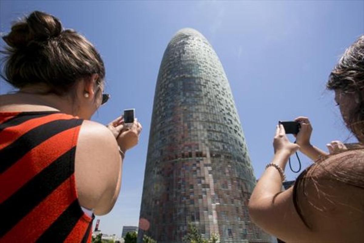 Dues turistes fotografien la torre Agbar.