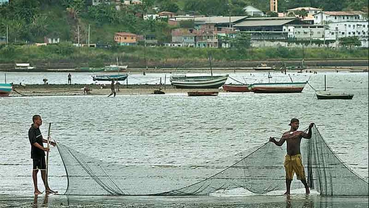 Dos pescadores preparan sus redes en una playa de Salvador.