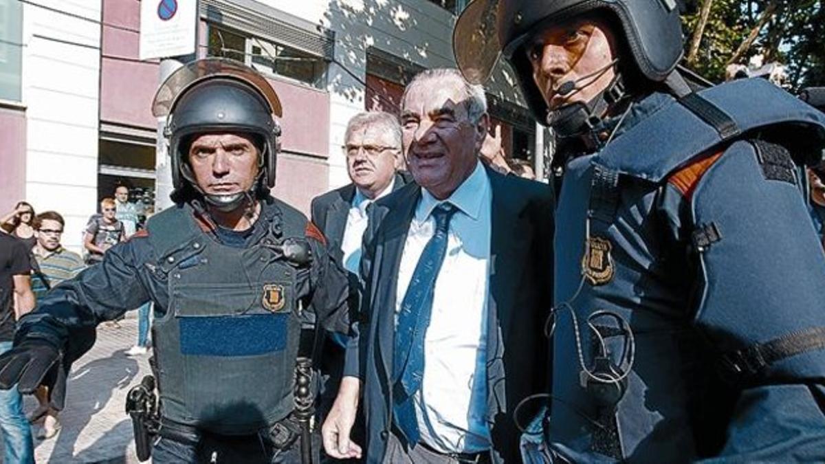 INSULTADO Y ZARANDEADO 3 El 'exconseller' Ernest Maragall es acompañado por varios agentes tras ser acosado por un grupo de indignados, ayer, en el parque de la Ciutadella, antes de entrar en la Cámara catalana.