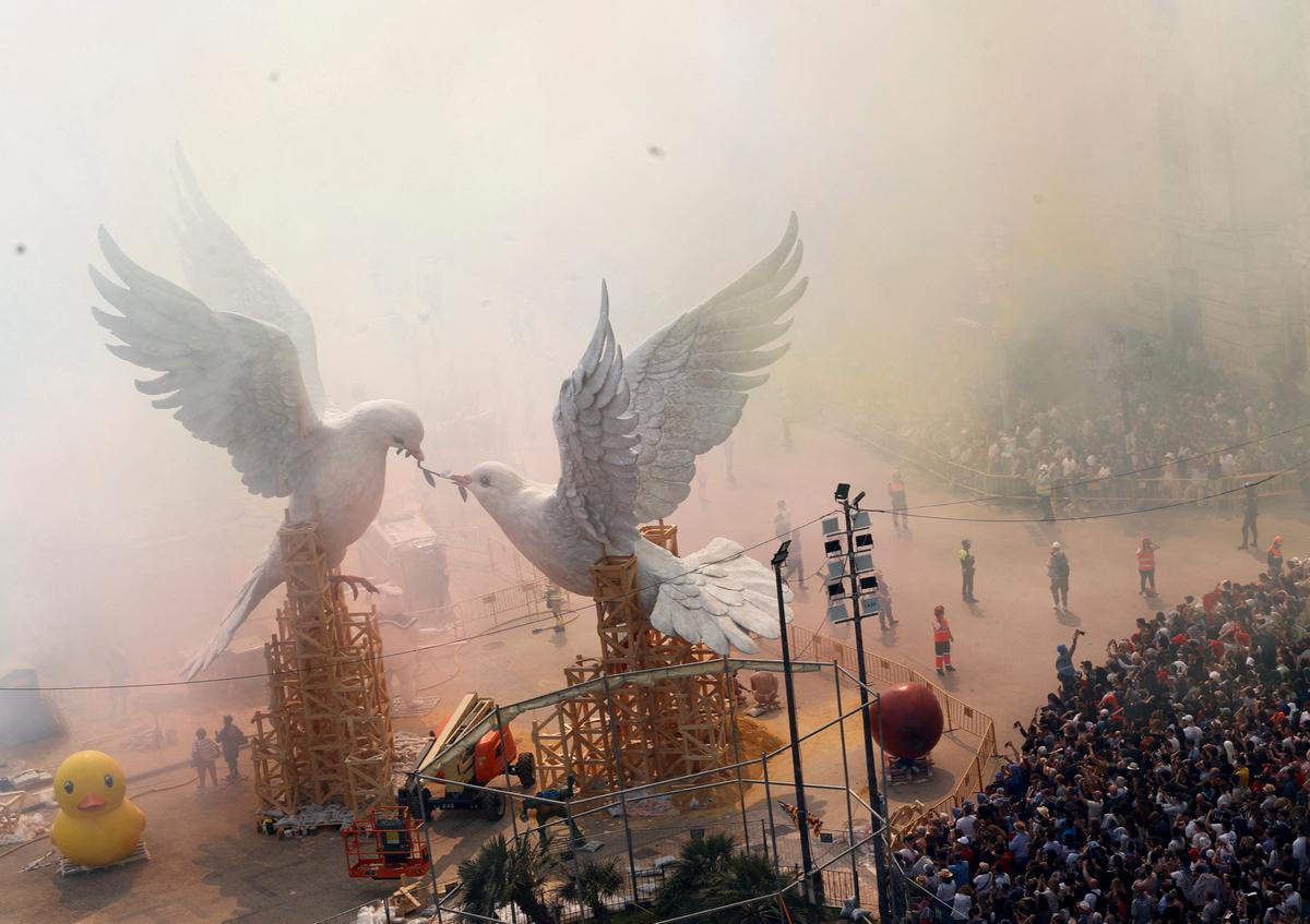 Smoke hides ninots or giant figures depicting doves of peace fighting over an olive branch by artist Escif, and the buildings of Plaza del Ayuntamiento during the Mascleta, an explosive barrage of firecrackers and fireworks during the traditional annual Fallas Festival, in Valencia, Spain, March 15, 2024. REUTERS/Eva Manez     TPX IMAGES OF THE DAY