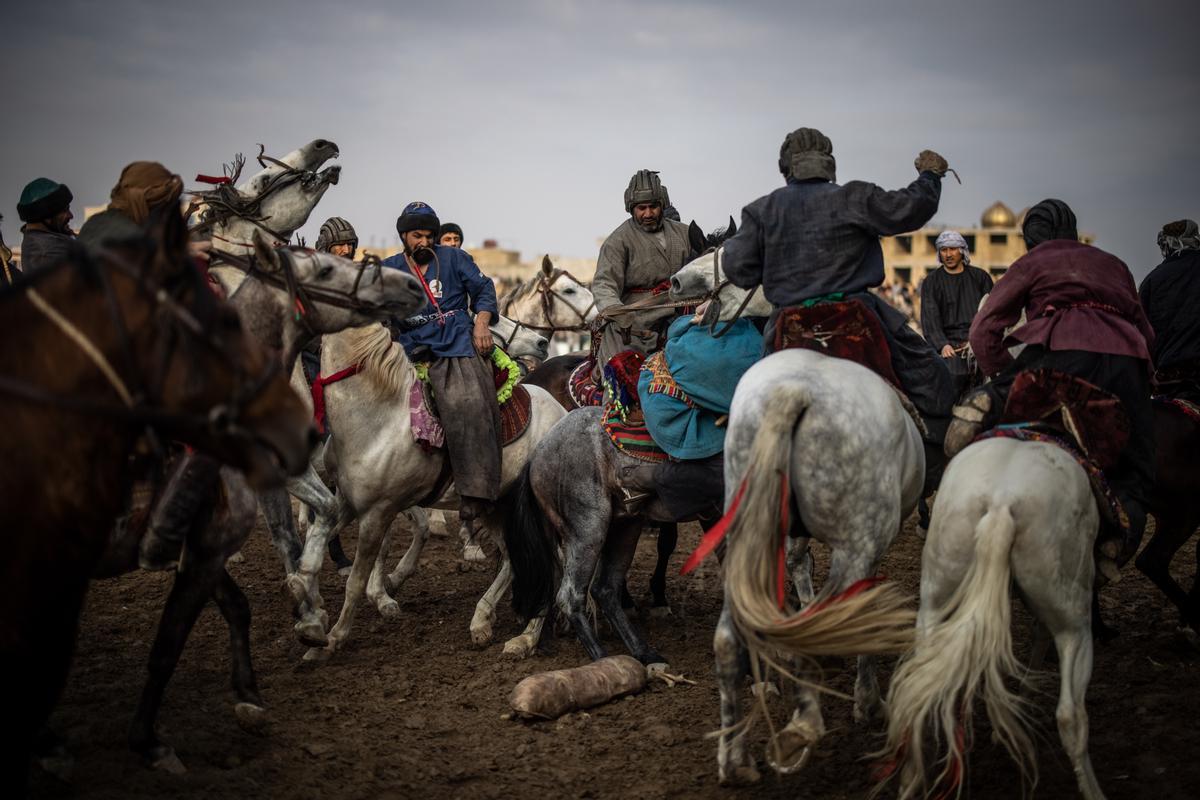 Jinetes afganos compiten en un deporte tradicional de Asia Central, en el que los jugadores montados a caballo intentan colocar una bolsa que se asemeja a un cadáver de cabra en una portería