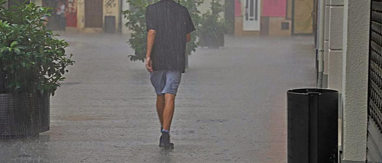 Un hombre camina bajo la intensa lluvia en Gandia. | LEVANTE-EMV