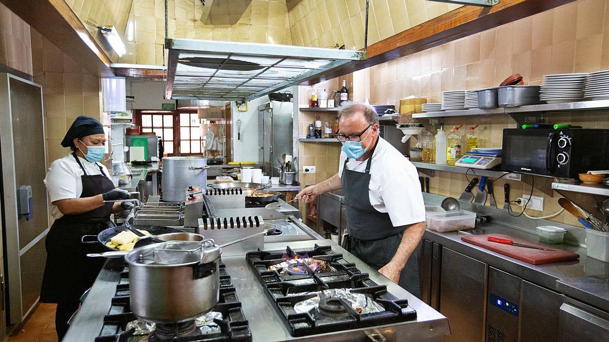 Manuel Veiga y una empleada preparan un servicio en la cocina del Meson El Gallego