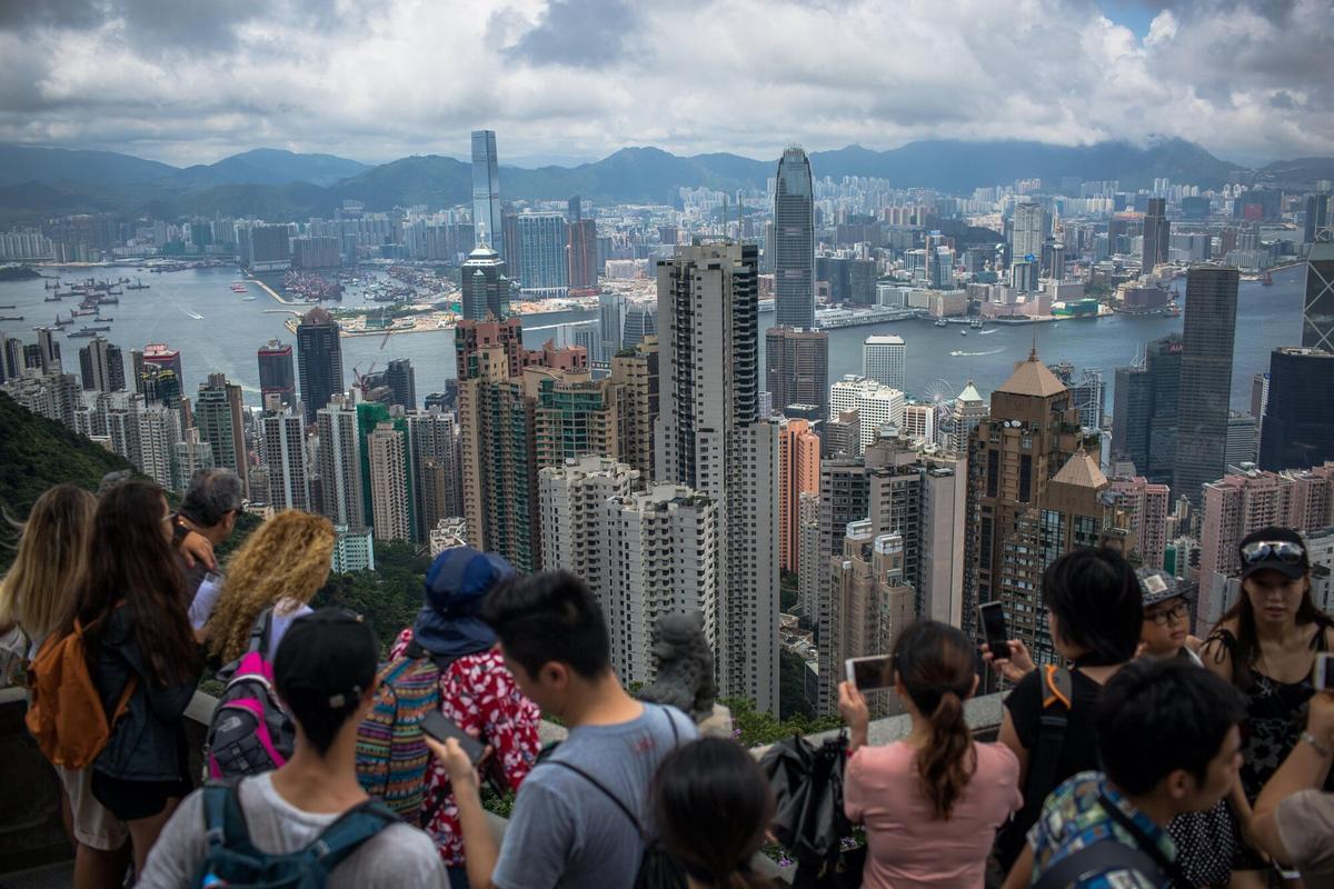 Turistes fan fotografies des del Victoria Peak als edificis comercials i residencials situats a banda i banda del port de Victoria, a Hong Kong.