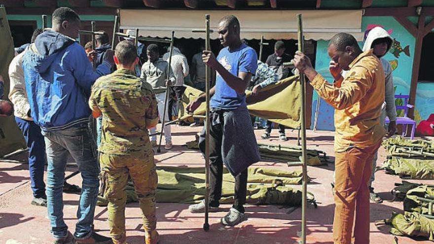 Una militar enseña a los migrantes a montar literas en la Misión Cristiana.