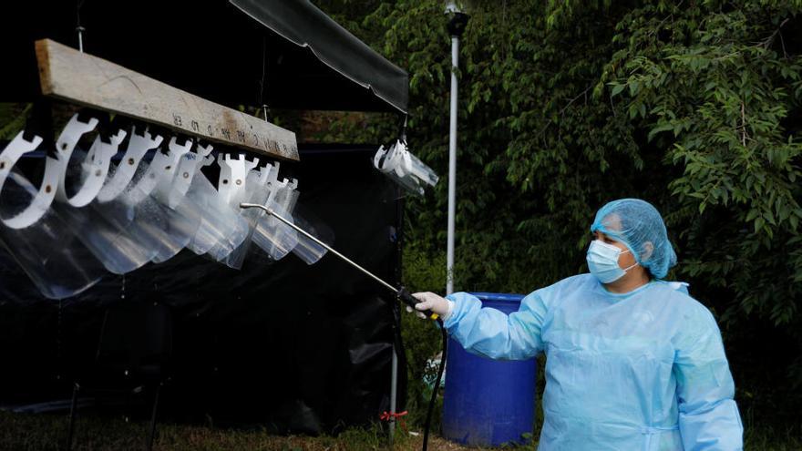 Una trabajadora de un cementerio desinfecta el equipamiento en El Salvador.