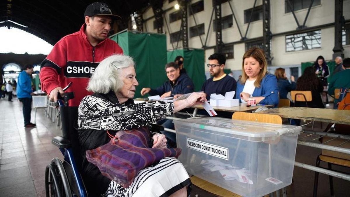 Una mujer mayor deposita su voto en una urna durante el referendum constitucional de Chile.