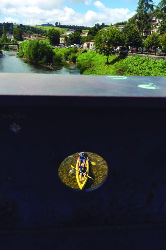 Una piragua vista desde el puente del Sella, con la localidad de Arriondas al fondo. | Miki López