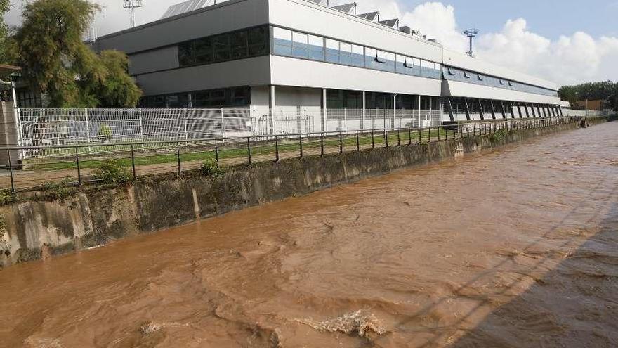 El Piles, a su paso por Las Mestas, con una importante crecida de sus aguas, de color marrón.