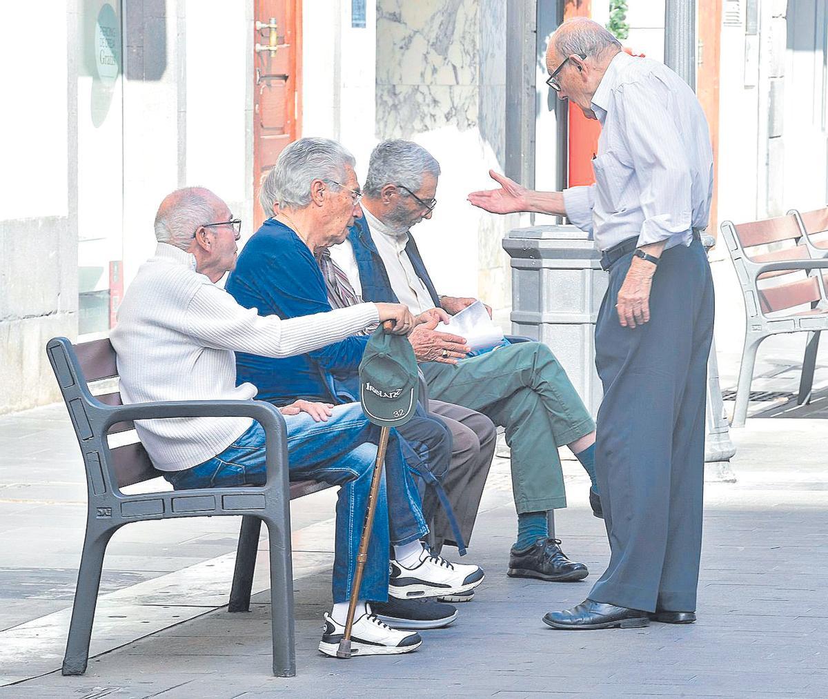 Un grupo de jubilados conversa en una calle de Triana.