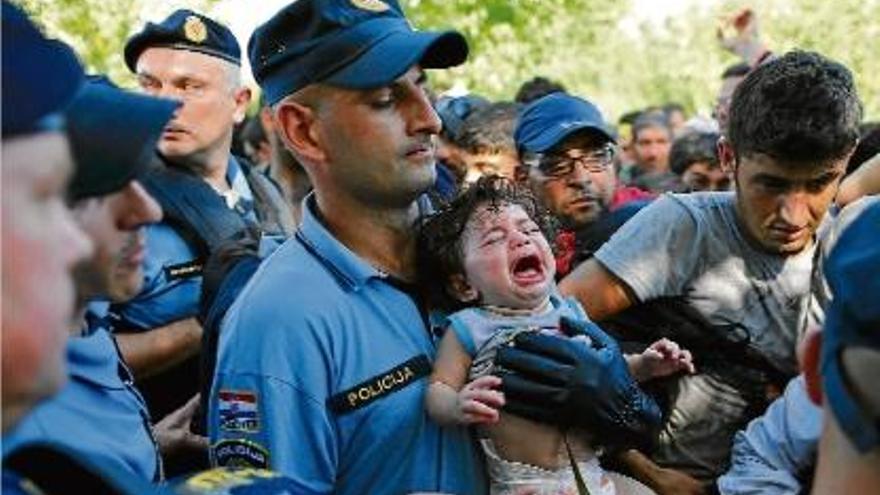 Un policia intenta calmar una nena que plora a la ciutat croata de Tovarnik.