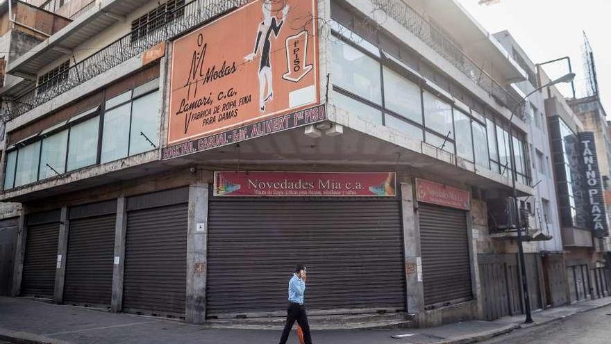 Un hombre camina frente a locales comerciales cerrados, ayer en Caracas. // Efe