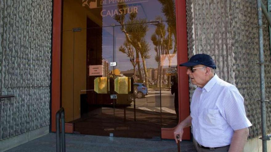 Un señor pasa delante del centro de pensionistas en Las Meanas, cerrado por vacaciones, según un cartel.