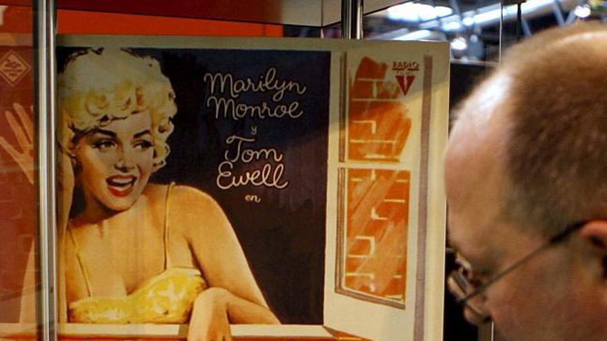 Una par de sandalias del modelo utilizado por Marilyn Monroe en la película ´La tentación vive arriba´ se exponen junto a un cartel del film en la exposición ´El vestuario en el cine empieza por los pies´, que se puede visitar estos días en la feria Modacalzado, en Madrid.