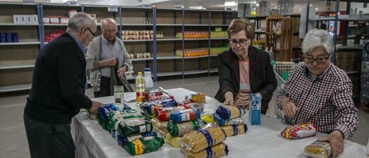 Voluntarios preparando los productos para entregarlos a los usuarios que acuden cada jueves al Economato de Cáritas Alcoy.