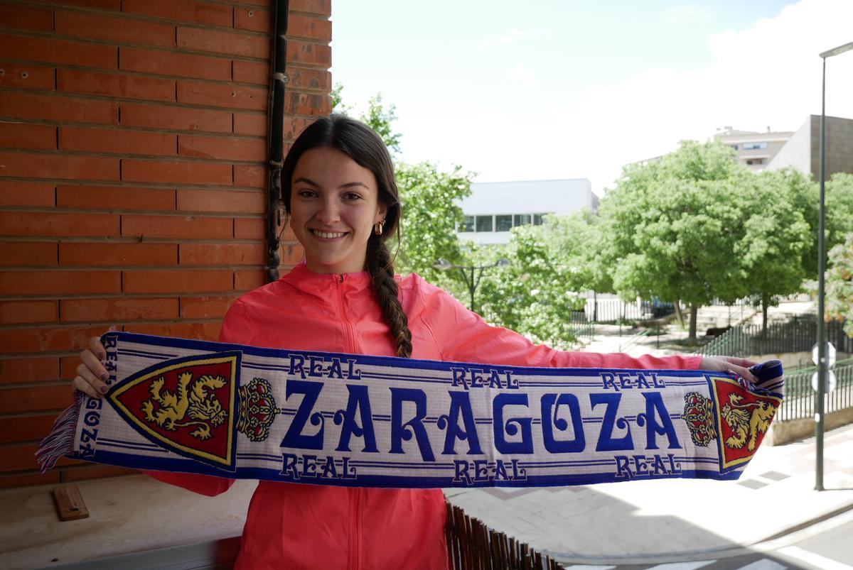 Paula, de 20 años, sonríe con la bufanda zaragocista desde el balcón de su piso situado en la calle Nayim.