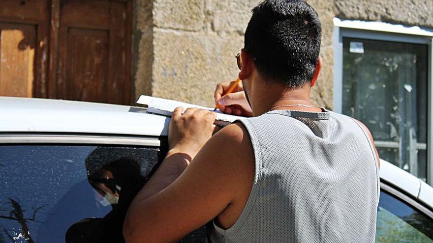Un joven firma apoyado sobre el techo de un coche. | A. Saavedra