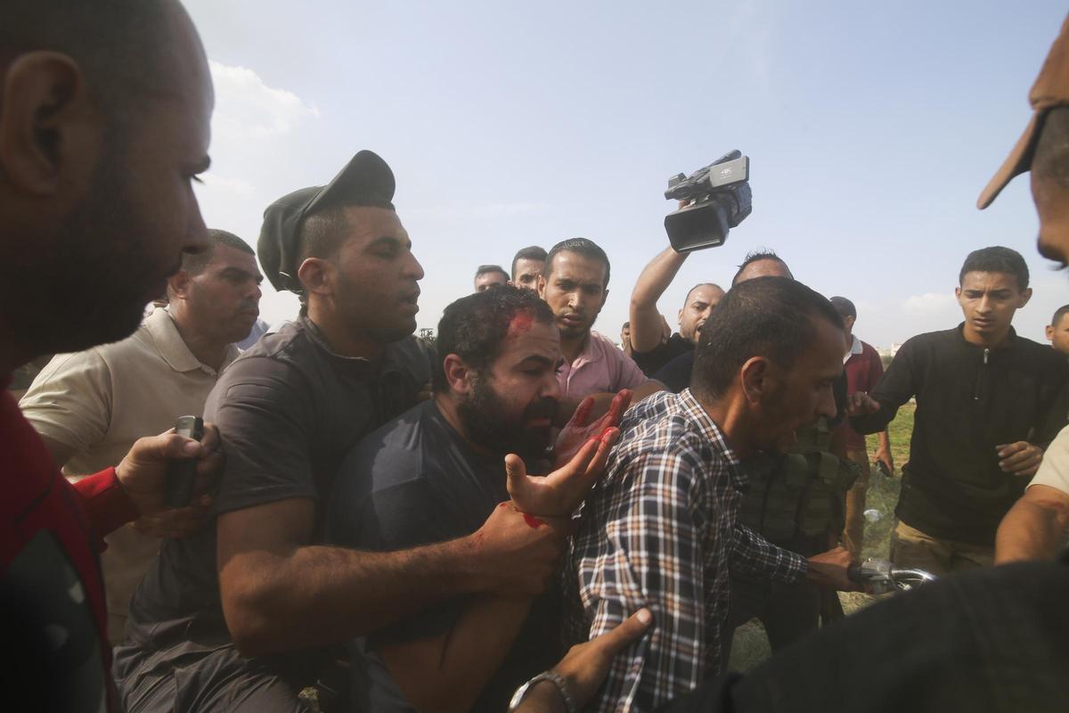 Ciudadanos palestinos trasladan a un civil israelí capturado (en el centro) de Kfar Azza hacia la Franja de Gaza.