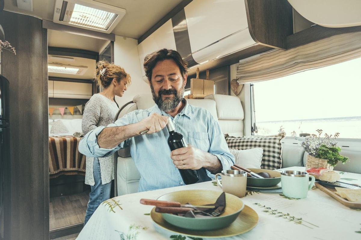 Pareja de viajeros adultos disfrutan de la hora del almuerzo dentro de una autocaravana